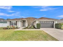 Single-story house with landscaped lawn and attached garage at 1570 Doves View Cir, Auburndale, FL 33823