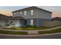 Two-story house with gray siding, attached garage, and landscaped front yard at 1576 Aspen Ave, Davenport, FL 33837