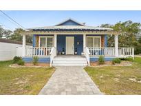 Charming blue house with white trim, front porch, and landscaped yard at 360 N Lake Shore Way, Lake Alfred, FL 33850