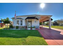 Single-story home with covered porch and carport, landscaped lawn, and red paver driveway at 1039 Motorcoach Dr, Polk City, FL 33868