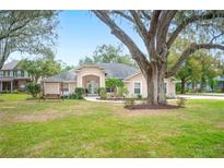 Beautiful home with mature landscaping and a large tree in the front yard at 1423 Royal Forest Loop, Lakeland, FL 33811