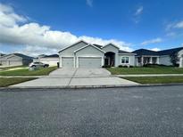 Gray house with three-car garage and landscaped lawn at 1543 Hollow Tree Ct, Lakeland, FL 33811