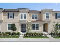 Tan two-story townhome with dark shutters, landscaping, and a tiled roof at 1559 Carey Palm Cir, Kissimmee, FL 34747