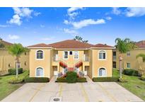 Tan two-story building with red staircases, surrounded by landscaping at 16202 Indian Creek Dr # 16202, Kissimmee, FL 34759