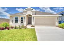 Beige house with two-car garage, landscaping, and driveway at 245 Piave St, Haines City, FL 33844