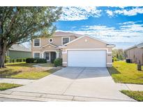 Charming two-story home featuring an attached two car garage, a manicured lawn, and mature landscaping at 4048 Windchime Ln, Lakeland, FL 33811