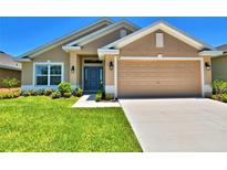 One-story house with tan exterior, two-car garage, and landscaped lawn at 527 Tanaro Ln, Haines City, FL 33844