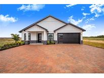 Modern farmhouse exterior boasts a brick driveway and attached garage at 2200 Mcclellan Rd, Frostproof, FL 33843