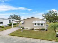 Tan single-wide manufactured home with carport and landscaped lawn at 3221 Pebble Bend Dr, Lakeland, FL 33810