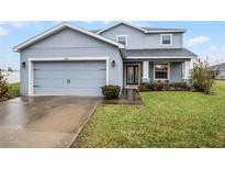 Two-story house with gray siding, attached garage, and landscaped lawn at 4185 Shearwater St, Lakeland, FL 33811