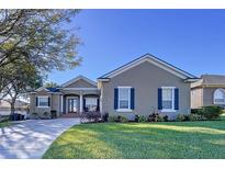 One-story house with a tan exterior, dark shutters, and a well-maintained lawn at 5825 High Ridge Loop, Lakeland, FL 33812