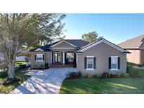 Tan house with dark shutters, lush landscaping, and a paved driveway at 5825 High Ridge Loop, Lakeland, FL 33812