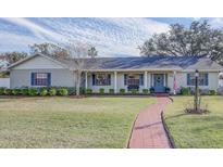 Brick ranch house with landscaped yard, walkway, and a blue door at 825 E Mann Rd, Bartow, FL 33830