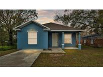 Newly constructed home with light blue exterior, driveway, and well-maintained lawn at 1033 Fleming Ave, Lakeland, FL 33815