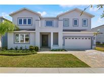 Two-story house with gray siding, a three-car garage, and a well-manicured lawn at 171 Golden Noble St, Kissimmee, FL 34747