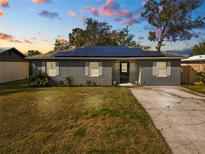 Gray house with solar panels, landscaping, and a driveway at 345 Piedmont Ct, Bartow, FL 33830