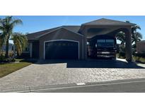 Tan house with a dark gray garage door and RV carport at 708 Teaberry Trl, Polk City, FL 33868