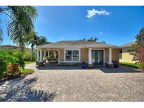 Charming single-story home with blue doors and a brick-paved driveway, surrounded by lush landscaping at 751 Meandering Way, Polk City, FL 33868