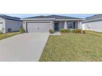 Well-maintained single-story home featuring a manicured lawn and a two-car garage at 1065 Silas St, Haines City, FL 33844