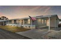 Gray manufactured home with covered carport and American flag at 2055 S Floral Ave # 235, Bartow, FL 33830