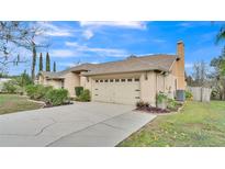 Beige single-story home featuring a spacious two-car garage and mature landscaping at 6244 Napa Dr, Lakeland, FL 33813