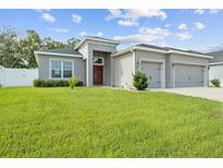 Gray house with two-car garage, lush lawn and red door at 8218 Wilder Loop, Lakeland, FL 33809