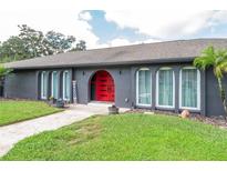 Charming single-story home with arched windows, a vibrant red door, and a well-maintained lawn at 280 Spring Lake Hills Dr, Altamonte Springs, FL 32714