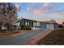 Charming single-story blue home featuring a screened porch, long driveway, and covered carport at 140 Jackson Park Ave, Davenport, FL 33897