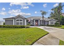 Charming one-story home with a well-manicured lawn, palm trees, and a driveway leading to a two-car garage at 335 Osprey Landing Way, Lakeland, FL 33813