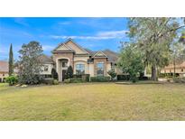 Elegant home showcasing a meticulously manicured lawn with lush landscaping and a stone accented facade at 6942 Indian Creek Park Dr, Lakeland, FL 33813