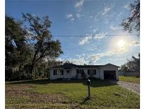 Charming one-story home with a well-maintained lawn and attached garage on a sunny day at 1560 Imperial Ave, Bartow, FL 33830