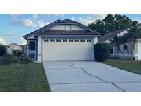 Attached two-car garage featuring decorative windows and a concrete driveway at 2021 Windward Pass, Lakeland, FL 33813