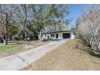 Charming single-story home with black garage door, front door, and a long driveway at 320 E Daughtery Rd, Lakeland, FL 33809