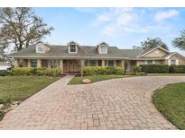 Charming single story home with brick accents, dormer windows, mature landscaping, and circular brick driveway at 4624 Kings Point Ct, Lakeland, FL 33813