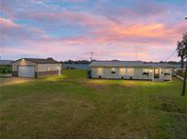 Inviting waterfront home featuring a lush green lawn, a metal roof, and a detached two-car garage at 5418 Cooper Ln, Fort Meade, FL 33841