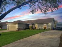 Charming single-story home featuring a well-manicured lawn and a paved driveway, accentuated by a beautiful sunset backdrop at 7965 Kaitlin Cir, Lakeland, FL 33810