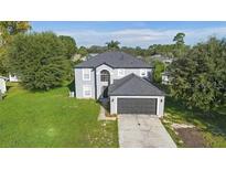 Two-story home with a gray roof, lush green lawn, and a two-car garage at 186 Rosedale Dr, Deltona, FL 32738