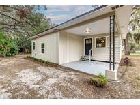 Charming home featuring a covered porch, black front door, and neutral siding, complemented by fresh landscaping at 2638 Ralph Rd, Lakeland, FL 33801