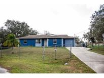 Charming single-story home with blue exterior, spacious front yard and a long driveway leading to an attached garage at 304 Olmo Ct, Winter Haven, FL 33880