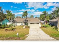 Charming home featuring a well-manicured lawn, a two-car garage, and a driveway, set under a blue sky at 7997 Kaitlin Cir, Lakeland, FL 33810