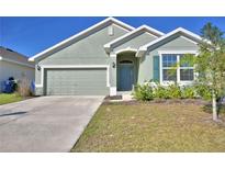 Charming single-Gathering home features a well-manicured lawn, two-car garage, and neutral-toned exterior paint at 136 Krenson Bay Loop, Winter Haven, FL 33881