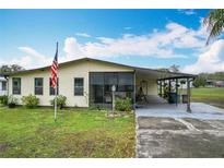 Charming single-story home features a spacious carport, an American flag and a well-manicured lawn at 3025 Canandaigua Trl, Lakeland, FL 33810