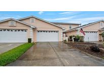 Charming townhome featuring a two-car garage, light pink exterior, and well-manicured lawn at 42 Enclave Dr, Winter Haven, FL 33884