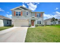 Charming two-story home featuring stone accents, a two-car garage, and a well-manicured lawn at 421 Chayne Pl, St Cloud, FL 34771