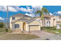 Two story home featuring a well-manicured lawn, brick driveway and an attached garage at 435 Gleneagles Dr, Davenport, FL 33897