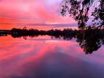 Beautiful view of a pink and purple sunset reflected over the lake at 5639 Water Oak Ln, Mulberry, FL 33860