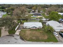 An aerial view of a single-Gathering home with a metal roof and lawn situated on a canal with lake access at 5716 Gibson Shores Dr, Lakeland, FL 33809