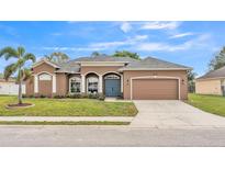 Charming single-story home featuring a well-maintained lawn, arched windows, and a two-car garage at 6987 Heatherbrook Dr, Lakeland, FL 33809