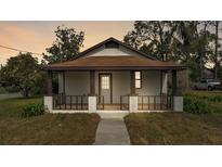 Charming home featuring a cozy front porch with decorative railing, a walkway, and mature trees at 1243 Olive St, Lakeland, FL 33815