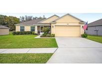 Inviting single-story home featuring a manicured lawn, a two-car garage, and charming landscaping at 1888 Creeks Vista Blvd, Lakeland, FL 33810